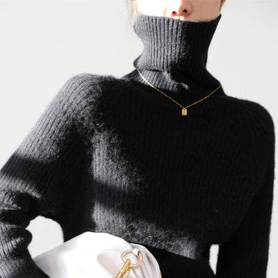 a woman in a black sweater holding a white purse